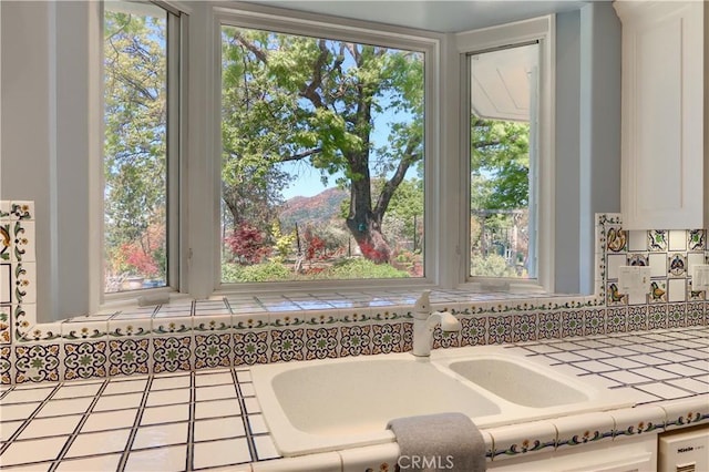 room details with a sink, tile counters, and white cabinetry