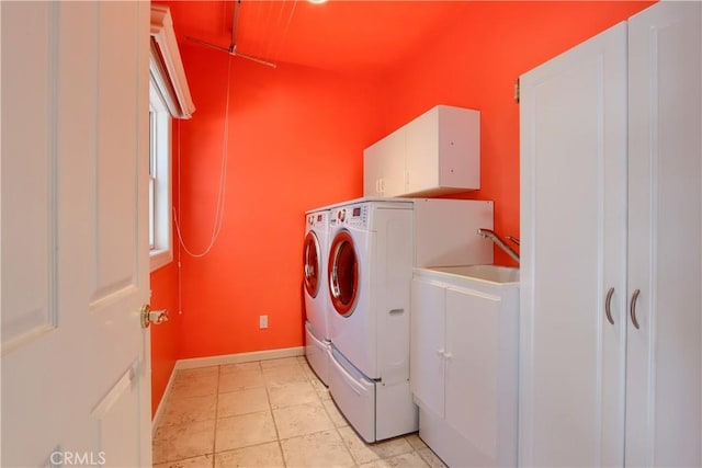 clothes washing area featuring separate washer and dryer, baseboards, a sink, and cabinet space