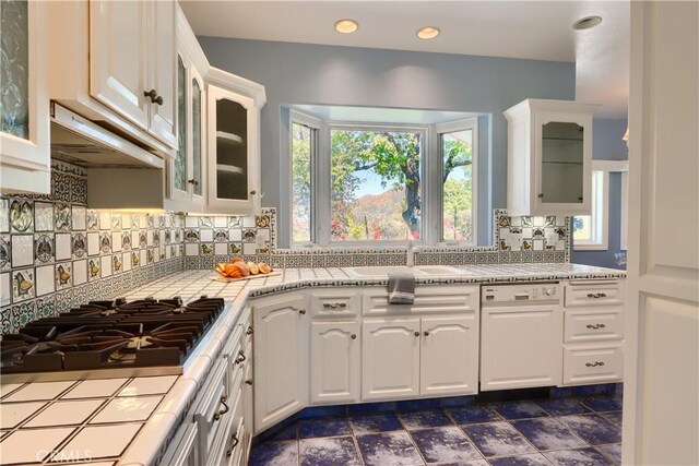 kitchen with glass insert cabinets, white cabinets, gas stovetop, decorative backsplash, and a sink