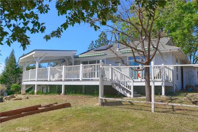 back of house featuring stairway, a deck, and a lawn