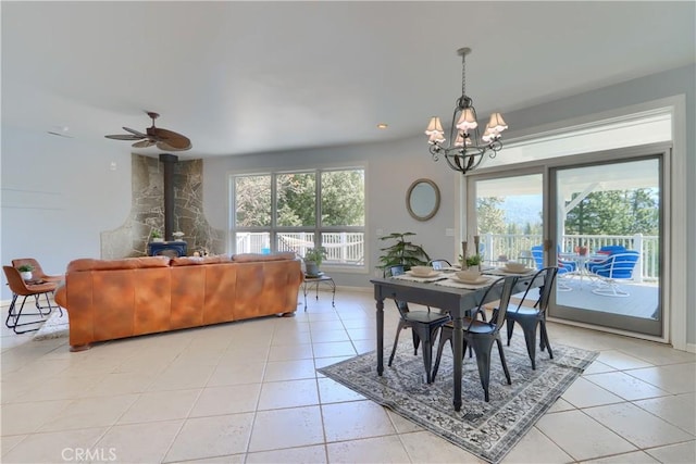 dining room with a chandelier, light tile patterned floors, baseboards, and a wood stove
