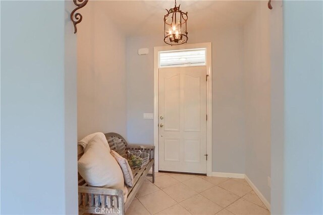 foyer featuring baseboards, an inviting chandelier, and light tile patterned flooring