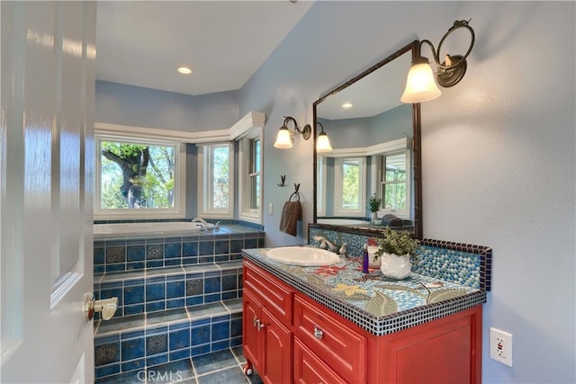 full bath with vanity and tiled bath