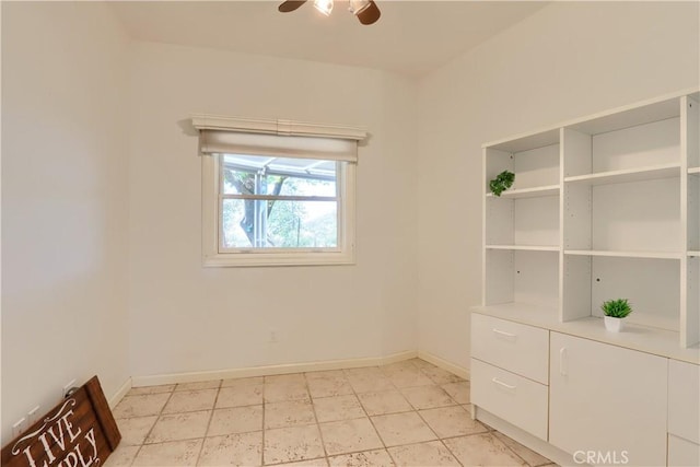 spare room with ceiling fan and baseboards