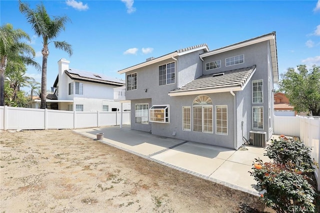 back of property with a fenced backyard, a tile roof, cooling unit, a patio, and stucco siding