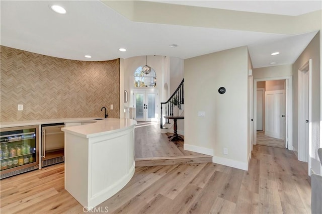interior space with light wood-style flooring, recessed lighting, light countertops, wine cooler, and baseboards