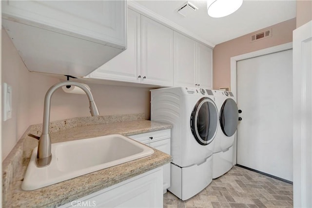 laundry room with a sink, visible vents, cabinet space, brick floor, and washing machine and clothes dryer