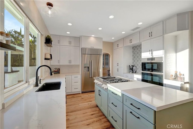 kitchen featuring tasteful backsplash, arched walkways, visible vents, appliances with stainless steel finishes, and a sink