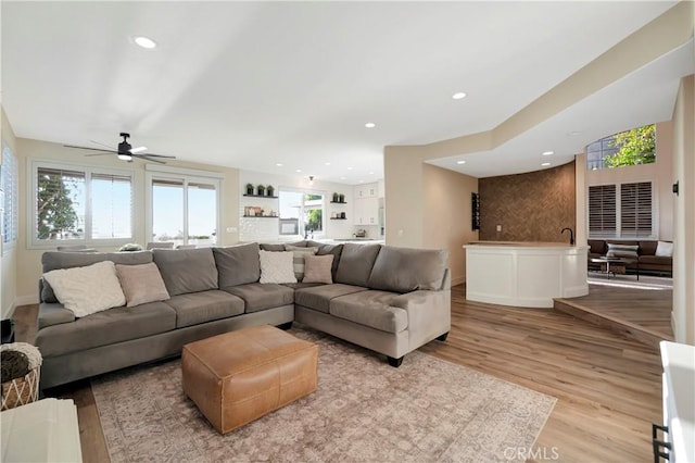 living area featuring light wood-type flooring, baseboards, a ceiling fan, and recessed lighting
