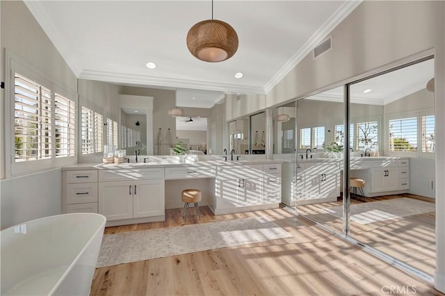 bathroom with a sink, ornamental molding, two vanities, and wood finished floors