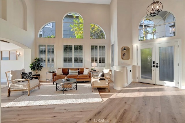 interior space featuring arched walkways, a towering ceiling, an inviting chandelier, and wood finished floors