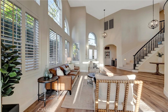 interior space with baseboards, a high ceiling, stairs, arched walkways, and wood finished floors