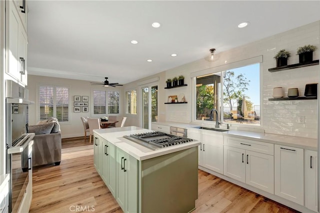kitchen featuring appliances with stainless steel finishes, open shelves, ceiling fan, green cabinetry, and a sink