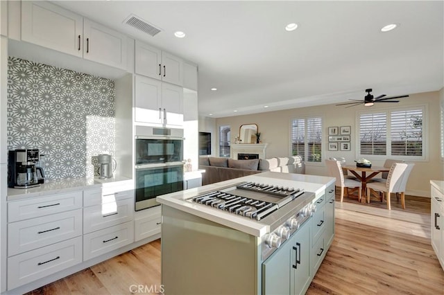 kitchen featuring a fireplace, visible vents, light countertops, and light wood-style flooring
