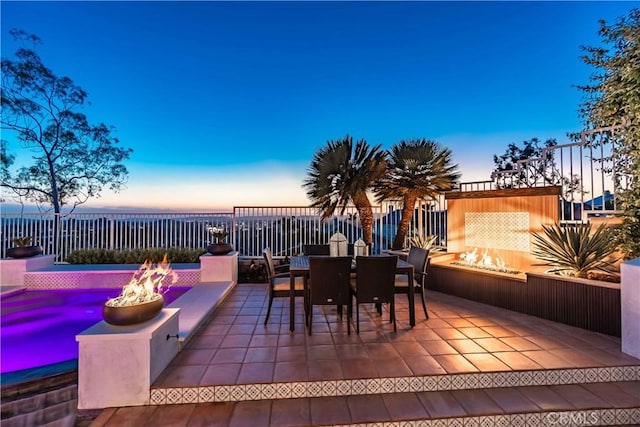 view of patio featuring outdoor dining area, fence, and a fire pit