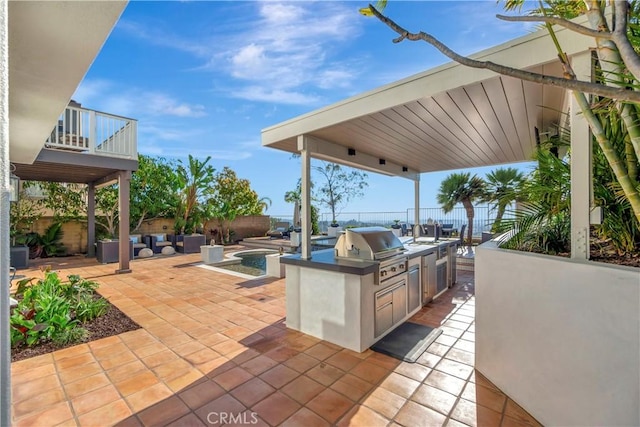 view of patio / terrace with a fenced backyard, a grill, a balcony, and an outdoor kitchen