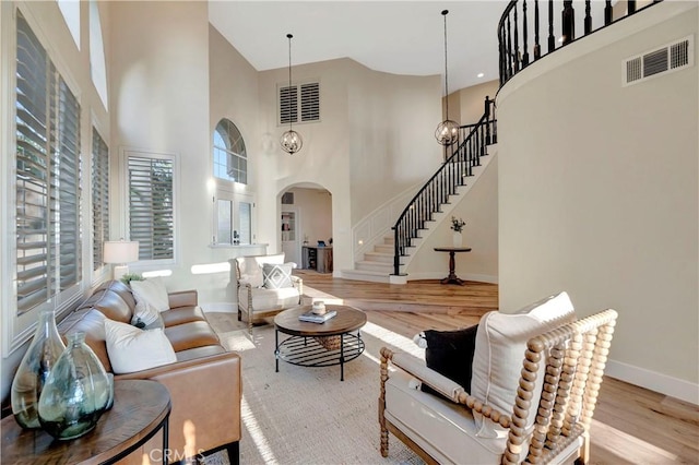 living room featuring arched walkways, stairway, visible vents, and wood finished floors