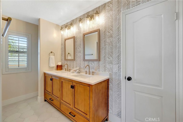 full bath featuring wallpapered walls, baseboards, and a sink