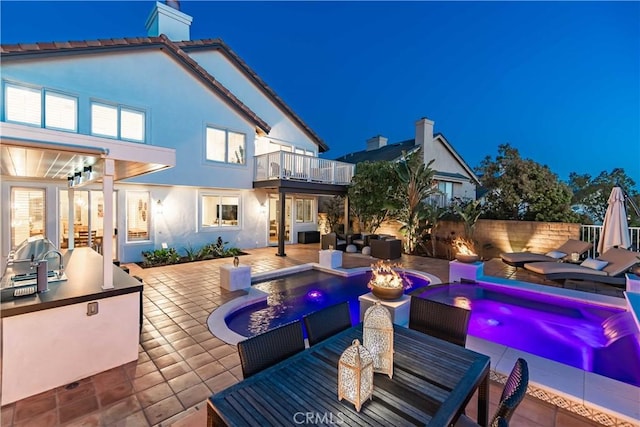 exterior space with exterior kitchen, fence, a balcony, outdoor dining space, and a fenced in pool