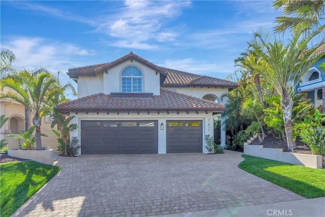 mediterranean / spanish house featuring stucco siding, decorative driveway, and a tile roof