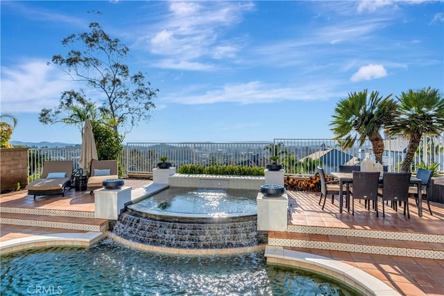 view of pool with a patio area, outdoor dining area, a pool with connected hot tub, and fence