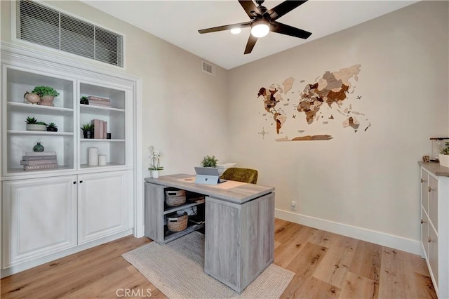 office area with light wood-style floors, visible vents, and ceiling fan