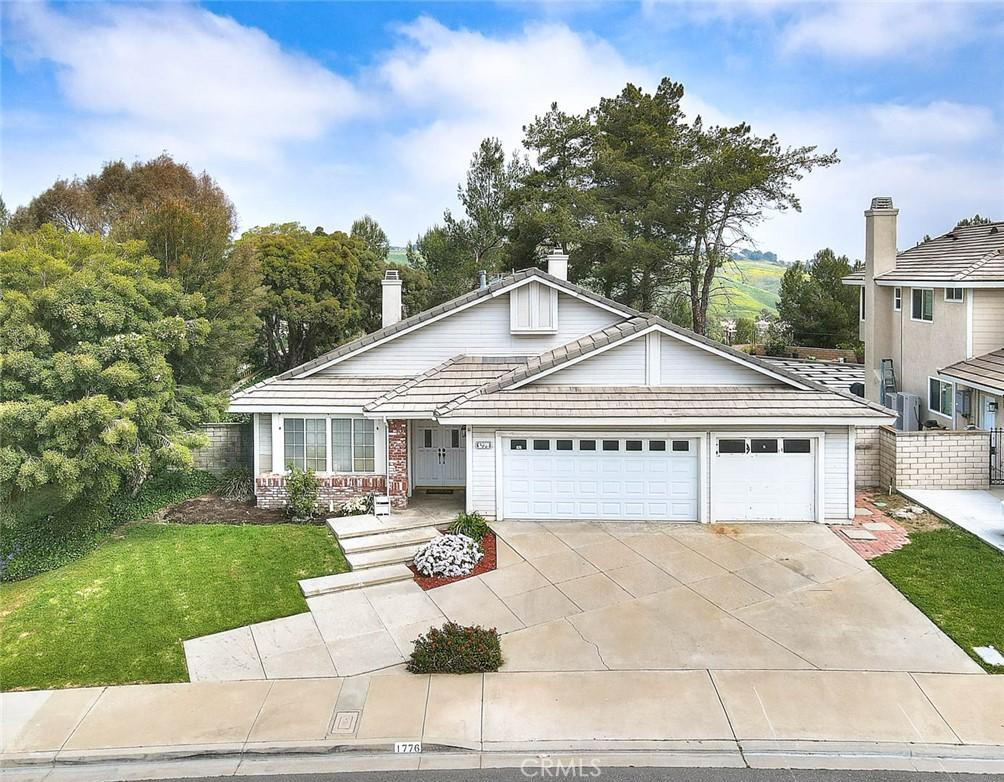 view of front facade featuring a chimney, driveway, a front yard, a garage, and a tiled roof