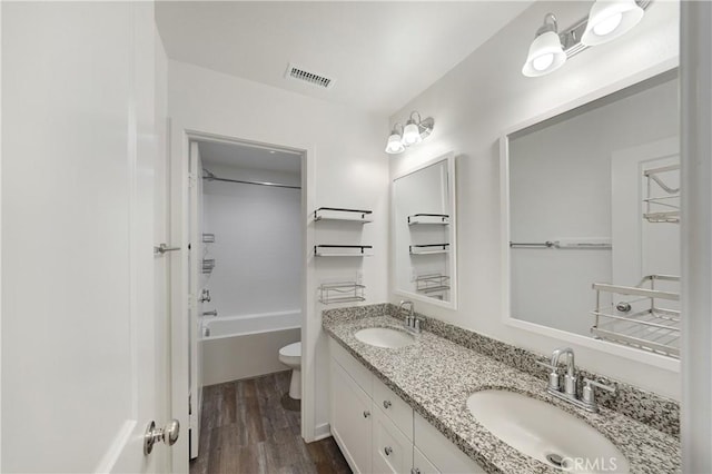 bathroom with a sink, visible vents, toilet, and wood finished floors