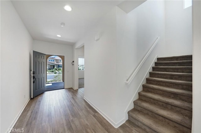 foyer entrance featuring baseboards, wood finished floors, recessed lighting, and stairway