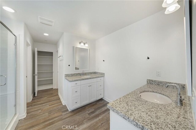 full bathroom featuring a shower stall, two vanities, and a sink
