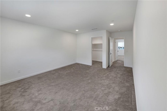 unfurnished bedroom featuring a closet, baseboards, carpet, a walk in closet, and recessed lighting