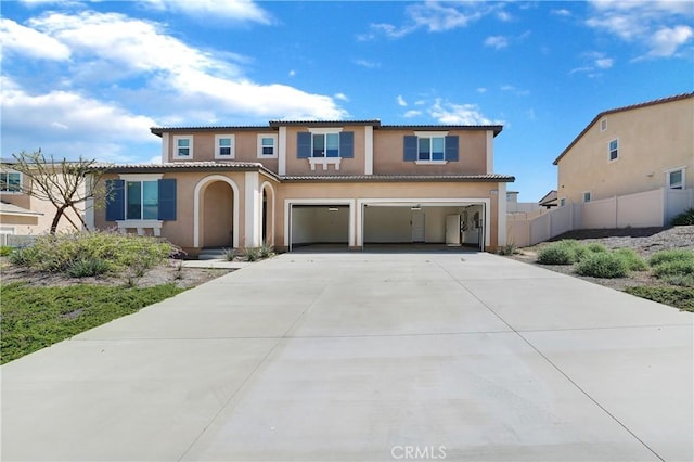 mediterranean / spanish-style home with a tiled roof, a garage, fence, concrete driveway, and stucco siding