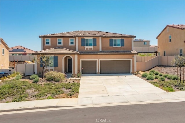 mediterranean / spanish home featuring stucco siding, fence, an attached garage, and a tile roof
