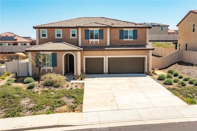 mediterranean / spanish-style home with a tiled roof, stucco siding, fence, an attached garage, and concrete driveway