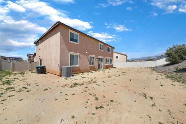 back of house with a fenced backyard, stucco siding, and central air condition unit