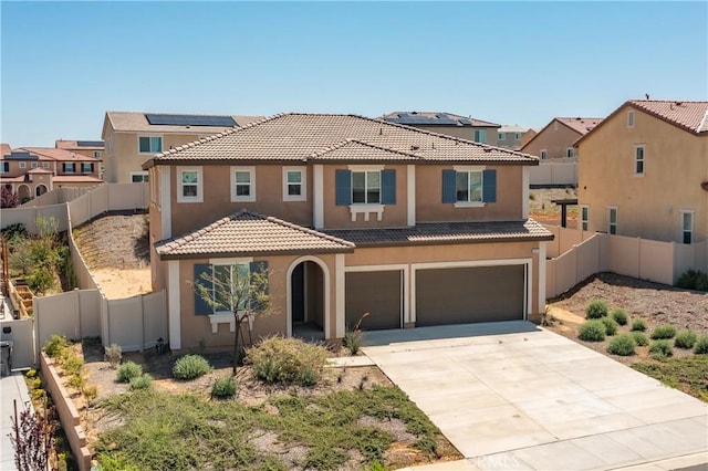 mediterranean / spanish house with a garage, a fenced backyard, a tile roof, stucco siding, and driveway
