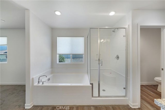 bathroom with toilet, a stall shower, baseboards, wood finished floors, and a garden tub