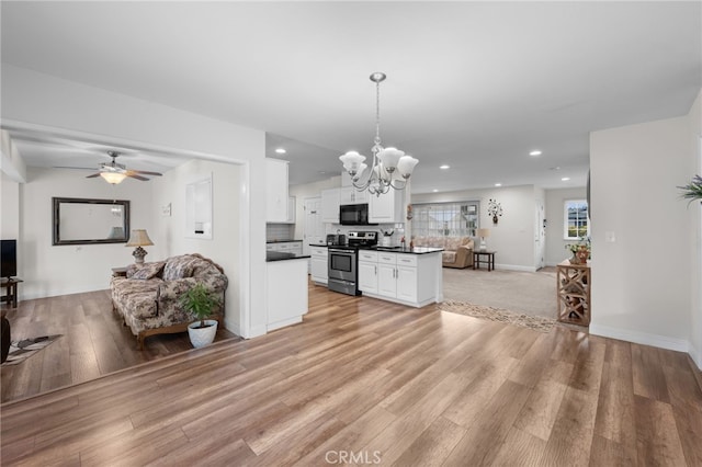 29423 Pebble Beach Dr, Menifee, CA 92586 - kitchen featuring stainless steel range with electric cooktop, black microwave, open floor plan, dark countertops, and a chandelier