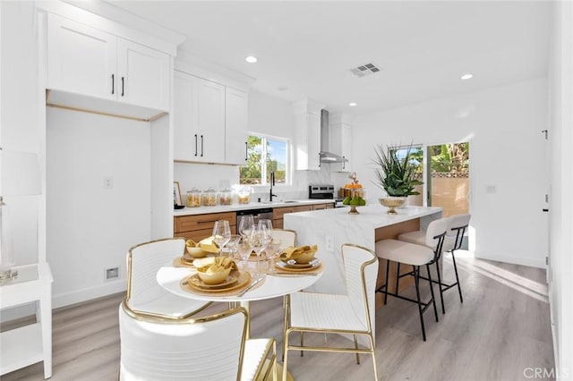 8491 Emerado Pl, Westminster, CA 92683 - kitchen with light wood finished floors, visible vents, a sink, wall chimney exhaust hood, and appliances with stainless steel finishes