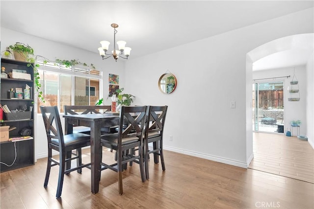 13564 Sylvan Oaks Rd, Victorville, CA 92392 - dining space with baseboards, arched walkways, an inviting chandelier, and wood finished floors
