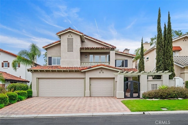 mediterranean / spanish-style house featuring decorative driveway, a gate, a garage, and stucco siding
