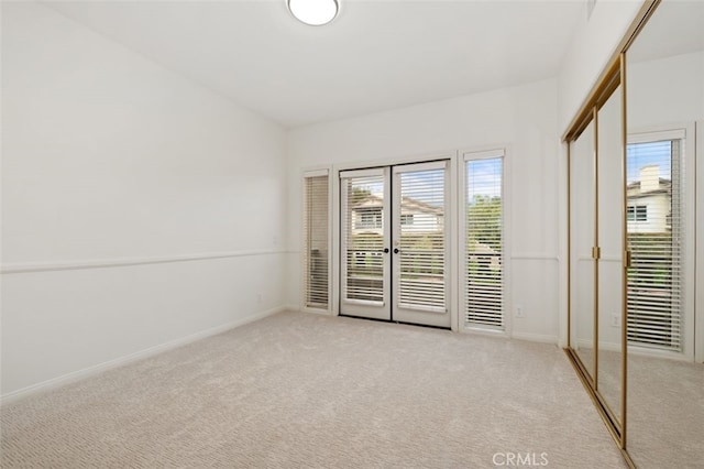 spare room featuring baseboards and light colored carpet