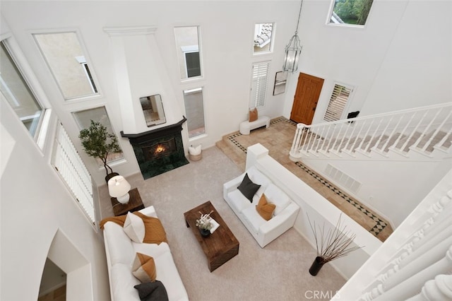 living area featuring visible vents, a high ceiling, and a lit fireplace