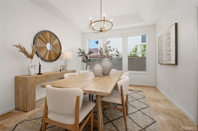 dining space with baseboards, stone finish flooring, a notable chandelier, and plenty of natural light