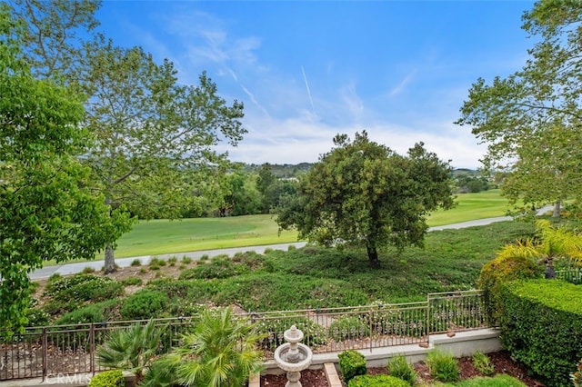 surrounding community featuring fence, view of golf course, and a lawn