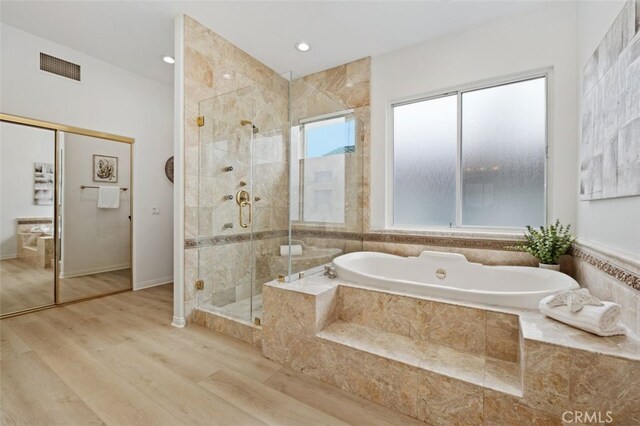 full bath featuring visible vents, a bath, a stall shower, and wood finished floors