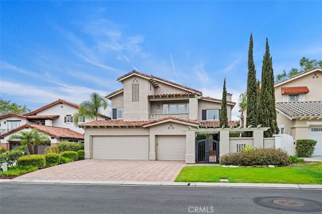 mediterranean / spanish-style home with an attached garage, a tile roof, fence, stucco siding, and driveway