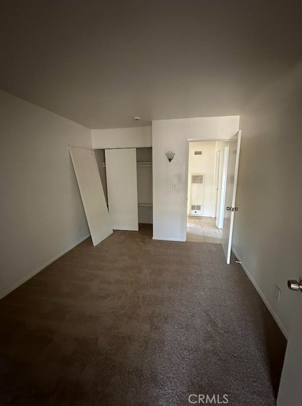 unfurnished bedroom featuring a closet, baseboards, and carpet floors