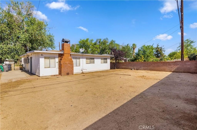 back of house featuring fence and a chimney