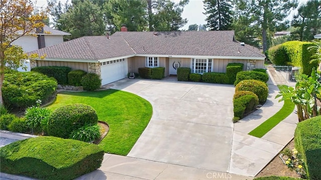 ranch-style home featuring stone siding, a garage, fence, a front lawn, and driveway